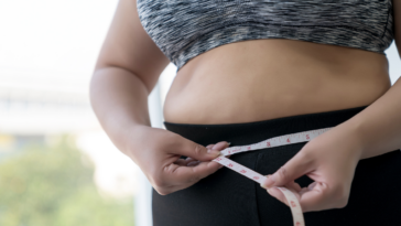 a woman measuring her waistline