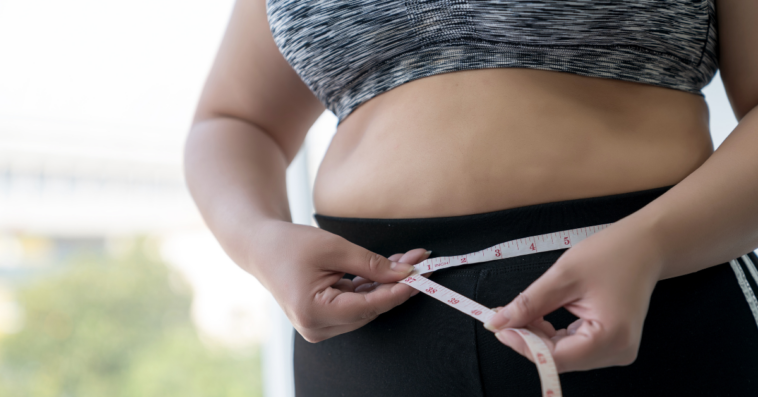 a woman measuring her waistline