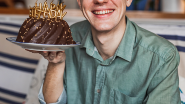 A young man holding a birthday cake.