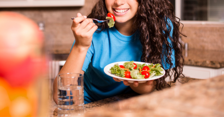 Teenage girl eating vegetables