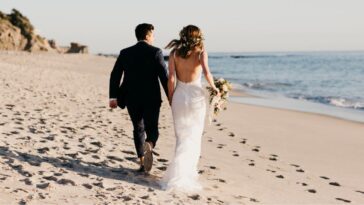 A couple walks hand in hand on the beach