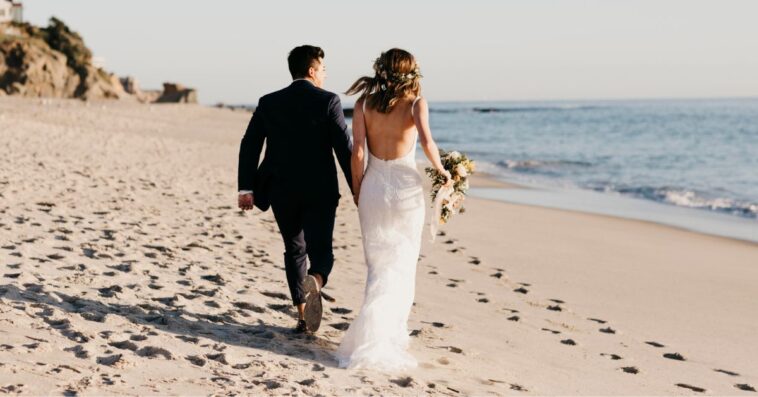 A couple walks hand in hand on the beach