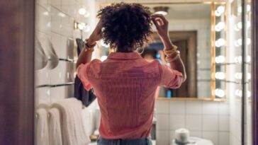A woman looks in the mirror while fixing her hair