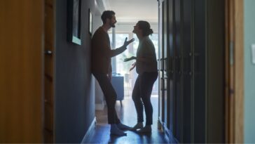 A couple argues in a hallway, in a home