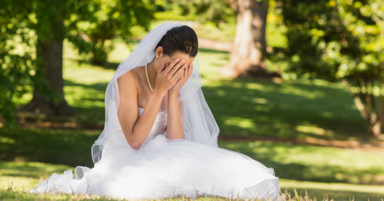Bride sitting on the ground and crying.