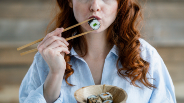 Woman holding a piece of sushi with chopsticks
