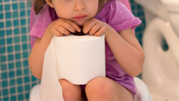 Young girl sitting on toilet
