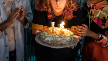 Teen girl blowing out birthday candles with friends