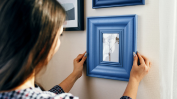 Woman looking at framed painting on wall.