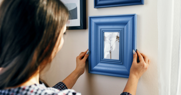 Woman looking at framed painting on wall.