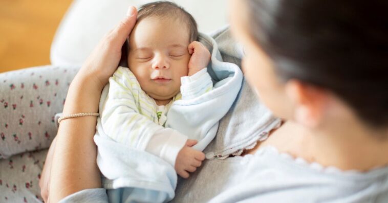 A woman holds a sleeping baby
