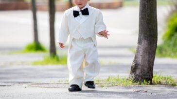 A young boy wanders around in a white tux