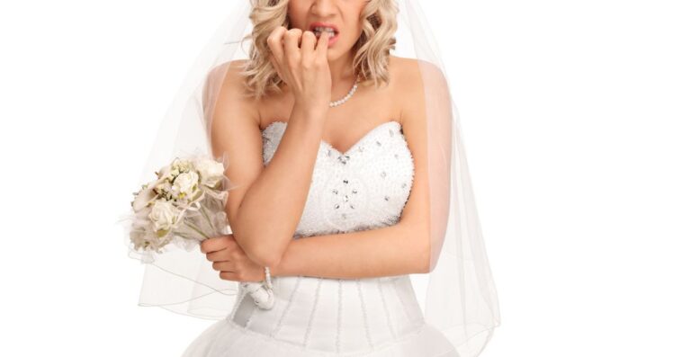 An upset bride gnaws at her pinky finger