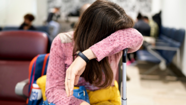 Woman crying over suitcase in waiting room.