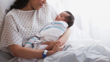 A woman in a hospital bed cradles a newborn