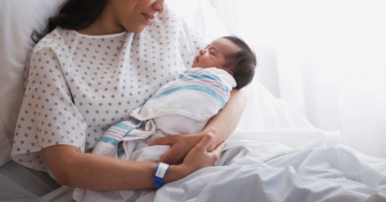 A woman in a hospital bed cradles a newborn