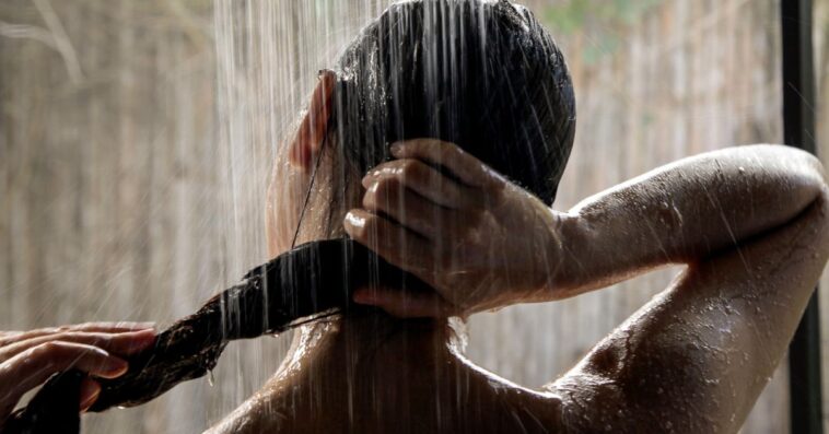 A woman in the shower extends her long hair