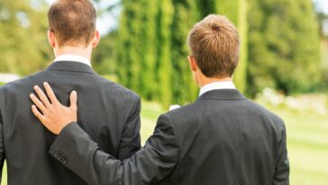 A groom and best man stand together looking away from the camera