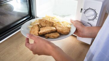 A person puts a plate of chicken nuggets into a microwave
