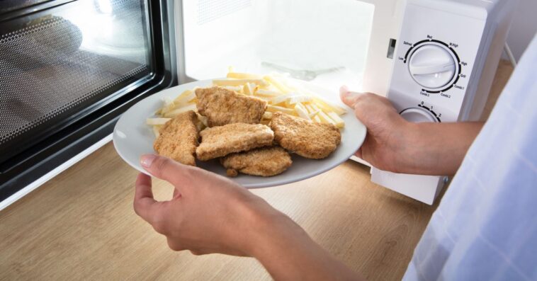 A person puts a plate of chicken nuggets into a microwave