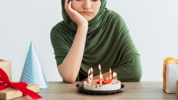 Teenage girl looking at her birthday cake unhappily