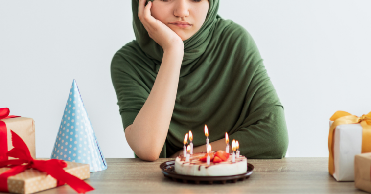Teenage girl looking at her birthday cake unhappily