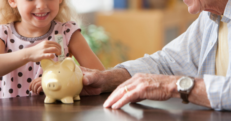Grandparent sharing a piggy bank with grandchild