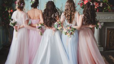A bride stands with her wedding party, two bridesmaids on either side of her