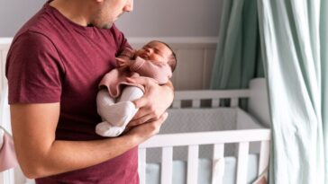 A man cradles a newborn baby