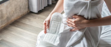 women in white towel holding menstrual pad