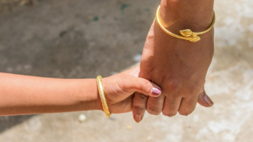 mother and daughter holding hands wearing gold gelang