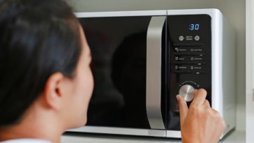 Asian woman using microwave