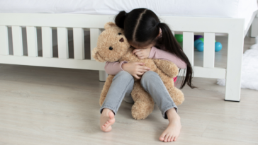 little girl crying over a teddy bear