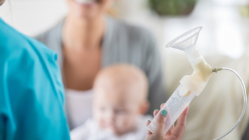 Mother holding a baby being shown a breast pump.