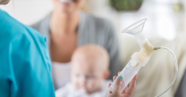 Mother holding a baby being shown a breast pump.