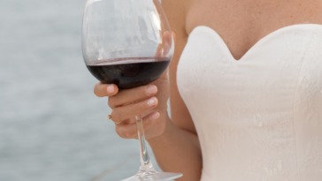 Bride holding a glass of red wine.
