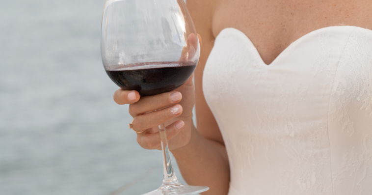 Bride holding a glass of red wine.