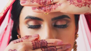 Cropped shot of a beautiful young Indian woman covering her face with her hands on her wedding day
