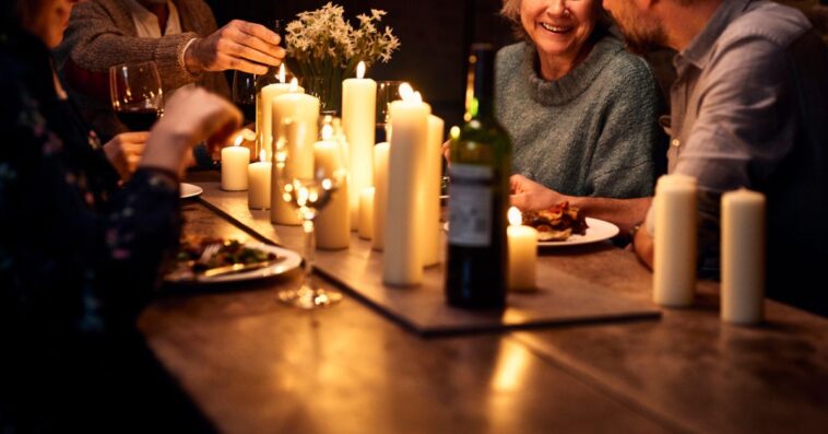 Couple dining with parents in restaurant, with wine and candles on the tables, relaxed dinner party