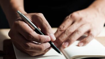 A close-up view of a man writing on a notepad