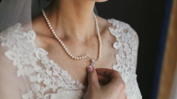 Beautiful bride holding expensive silver necklace with pearls on neck.