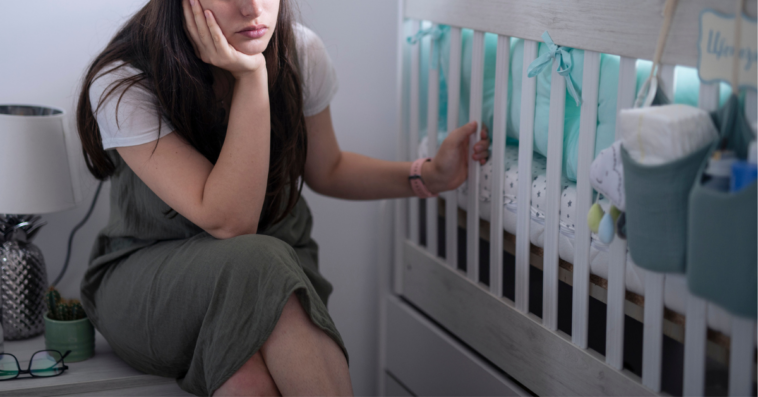 grieving mother seated by empty crib
