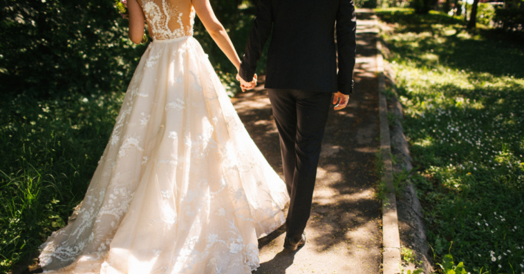 bride and groom walking down path holding hands