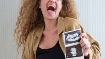 woman celebrating her pregnancy while holding ultrasound images