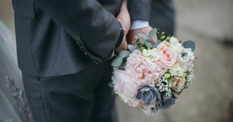Groom holding flowers at wedding