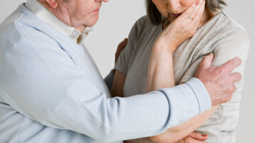 Elderly man caressing elderly woman.