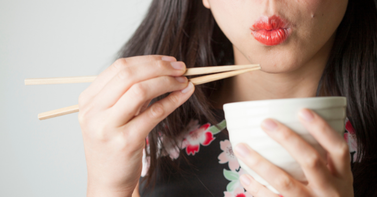 A woman eating using chopsticks.