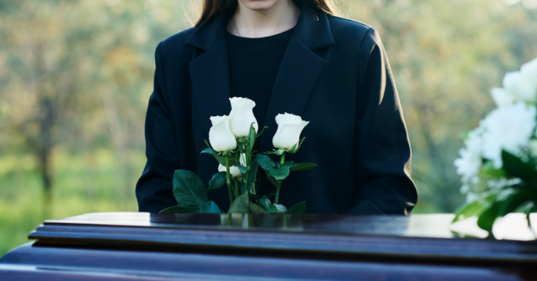Young woman standing above a coffin.