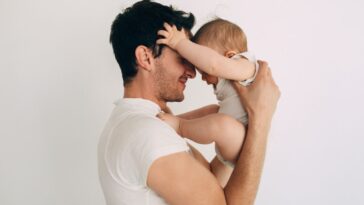 Man holding a baby face to face and smiling