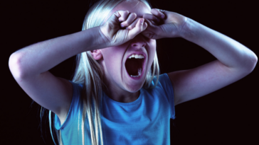 Girl screaming with her eyes covered.